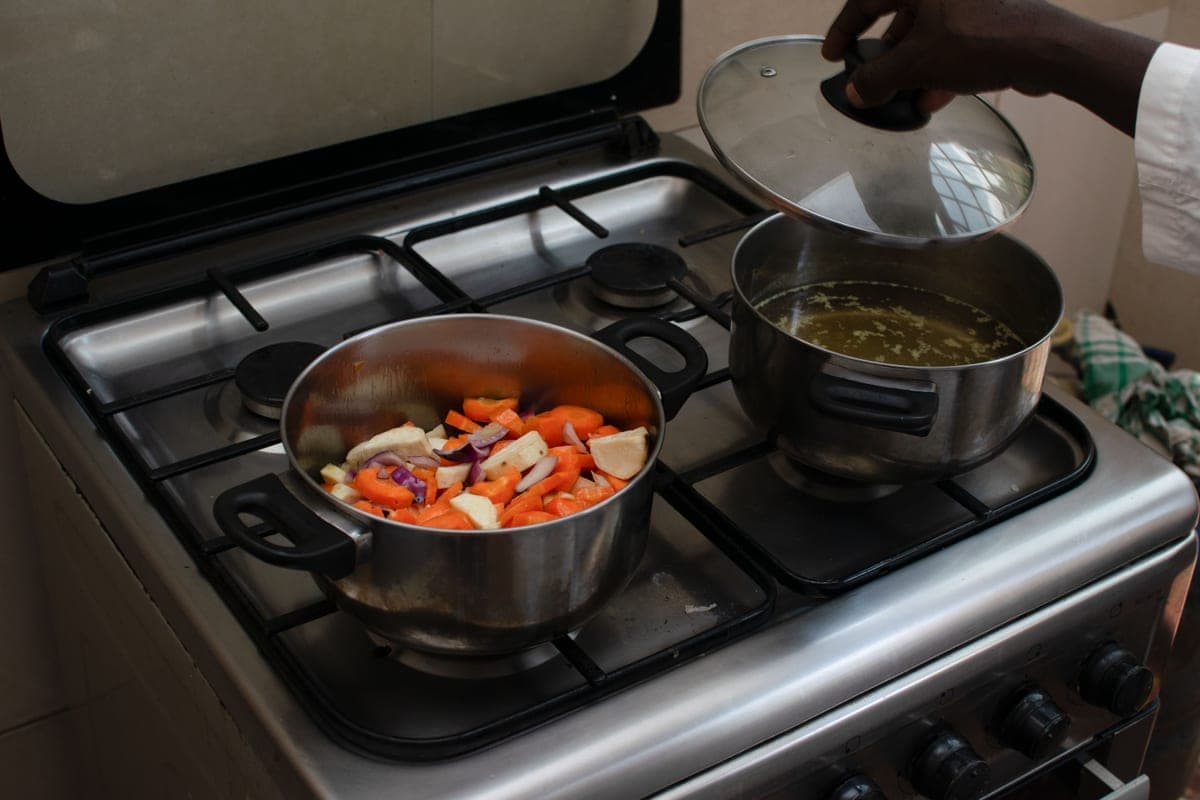 A pan of vegetables cooking on a stovetop, photographed from above.